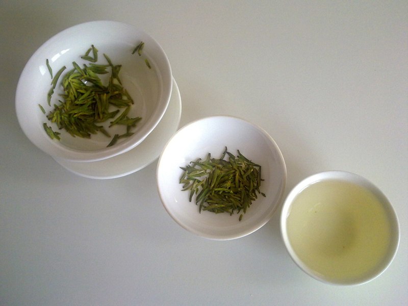 Tea tree leaves and a cup of green tea.